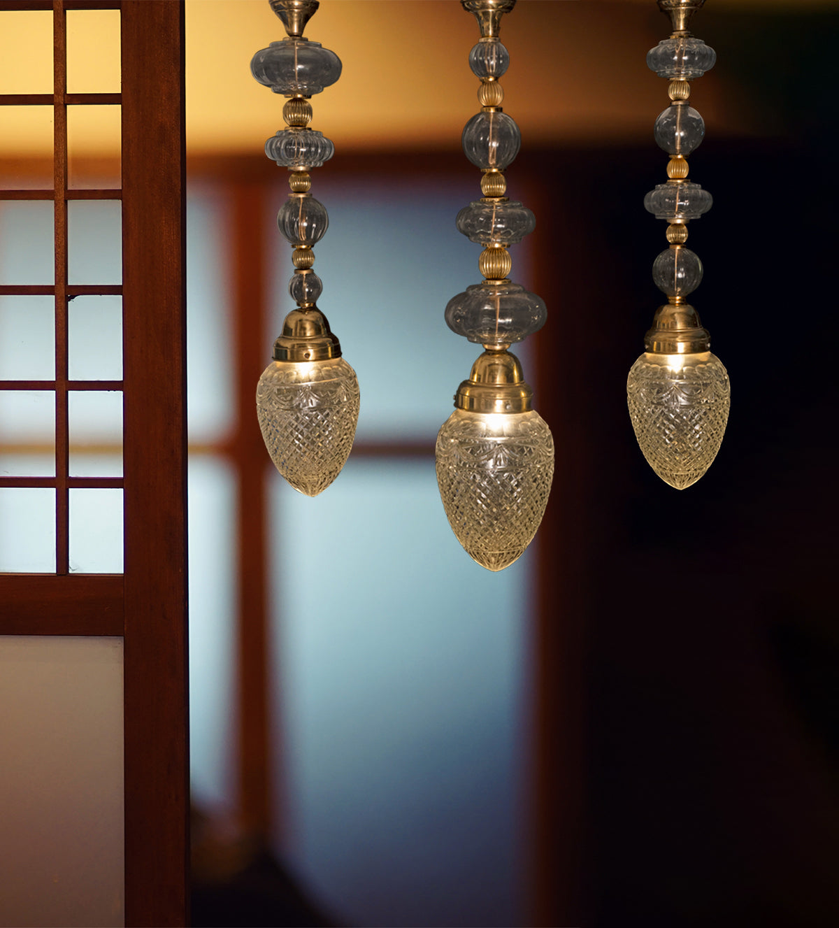 Imperial Brass Crystal Pendant Light with intricate brass accents and shimmering crystal globes, creating a luxurious, warm ambiance ideal for high-ceiling spaces.
