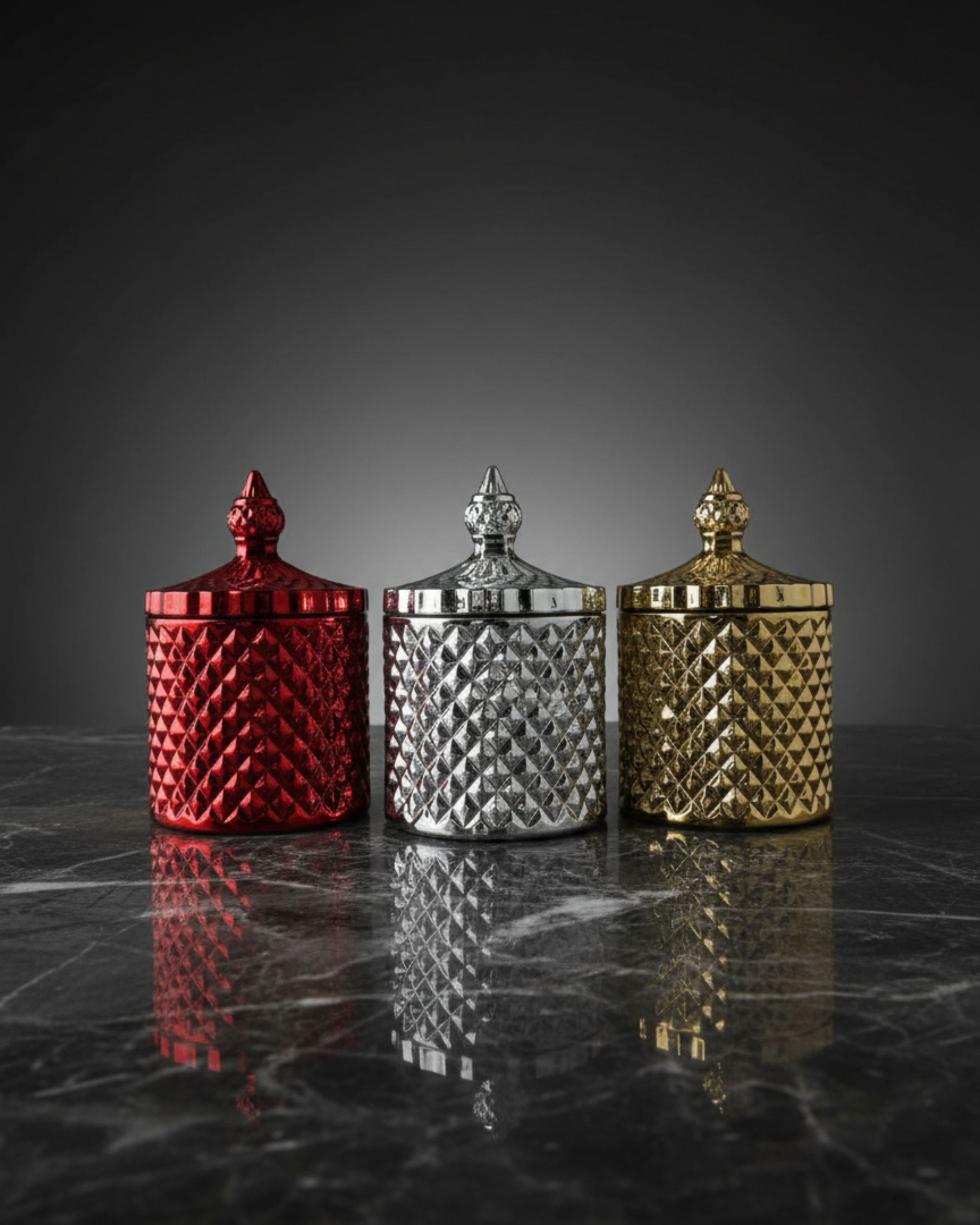 Three decorative jars in red, silver, and gold on a dark marble surface.