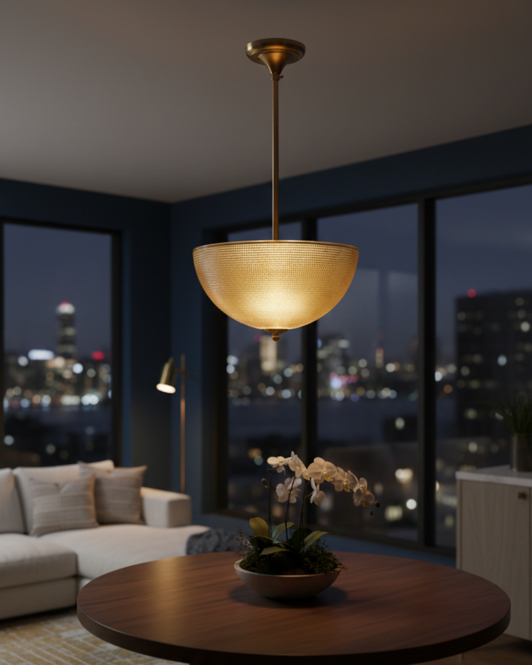 Living room with a pendant light fixture and city skyline view. Discover Aurelia Bowl Luxe Pendant Light by AartaaDecor. Handcrafted solid brass & textured glass pendant, made in India.