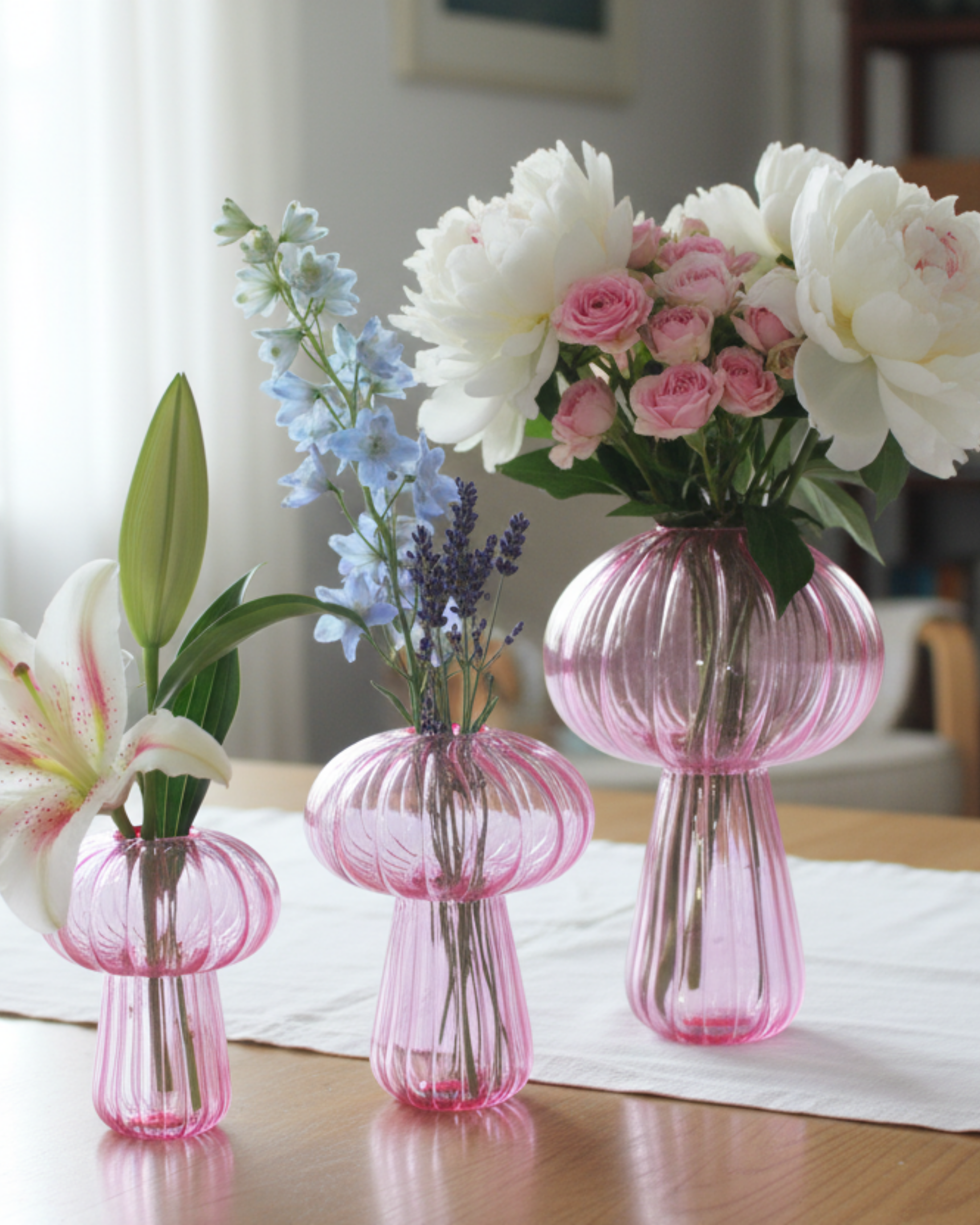 Set of pink glass vases with flowers on a table