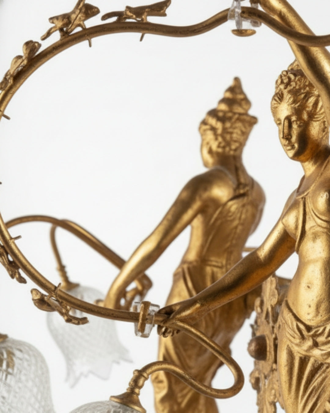 Gold-colored decorative item with two figures holding a wreath against a white background