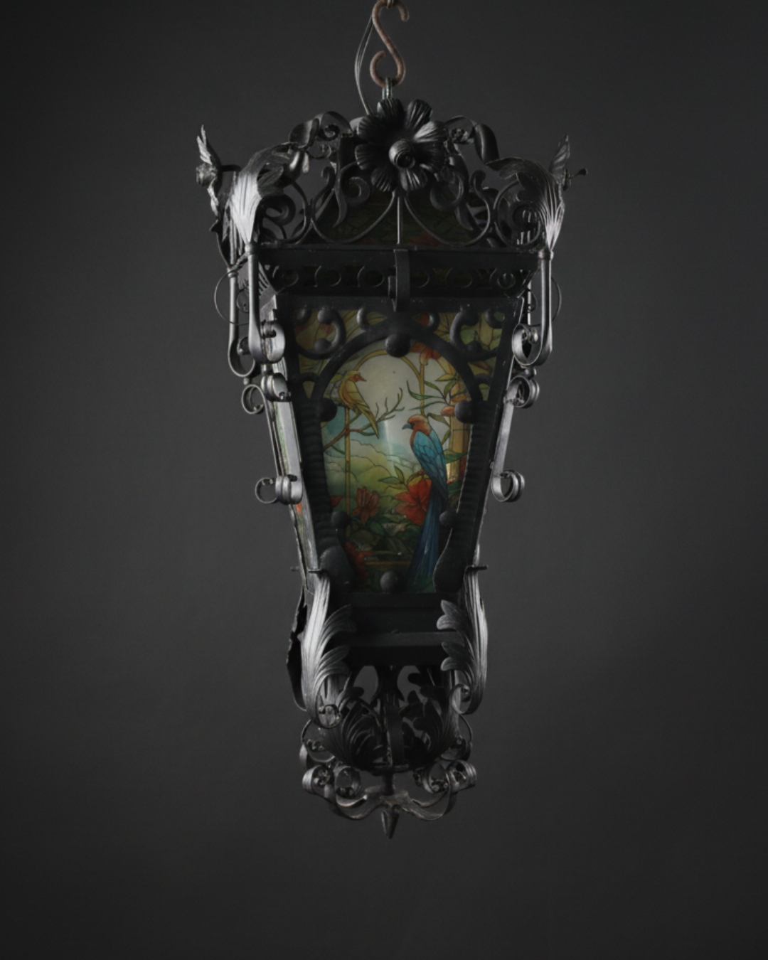 Decorative hanging lantern with intricate carvings and a colorful central panel on a dark background