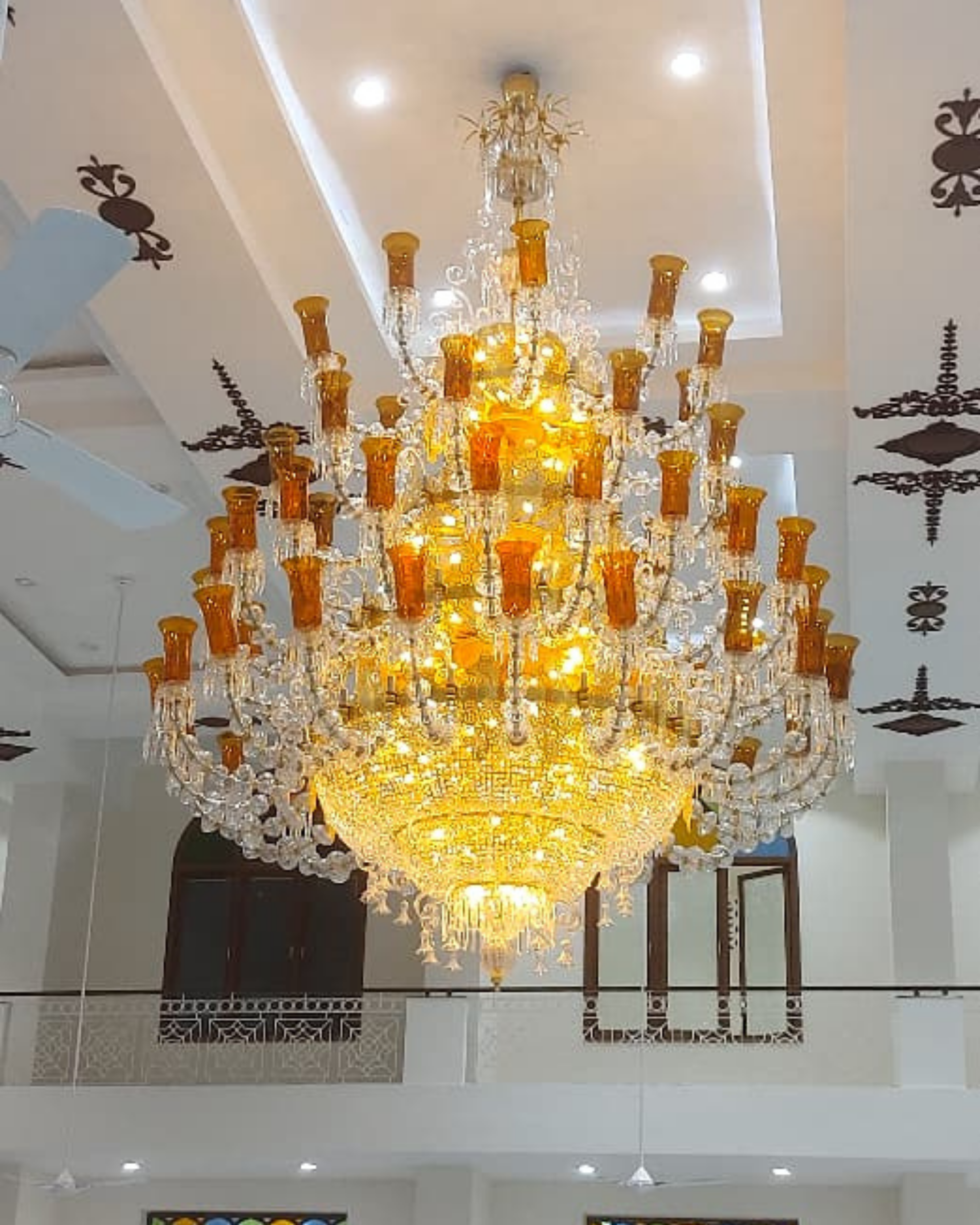 Large ornate chandelier hanging in a room with decorative ceiling designs.