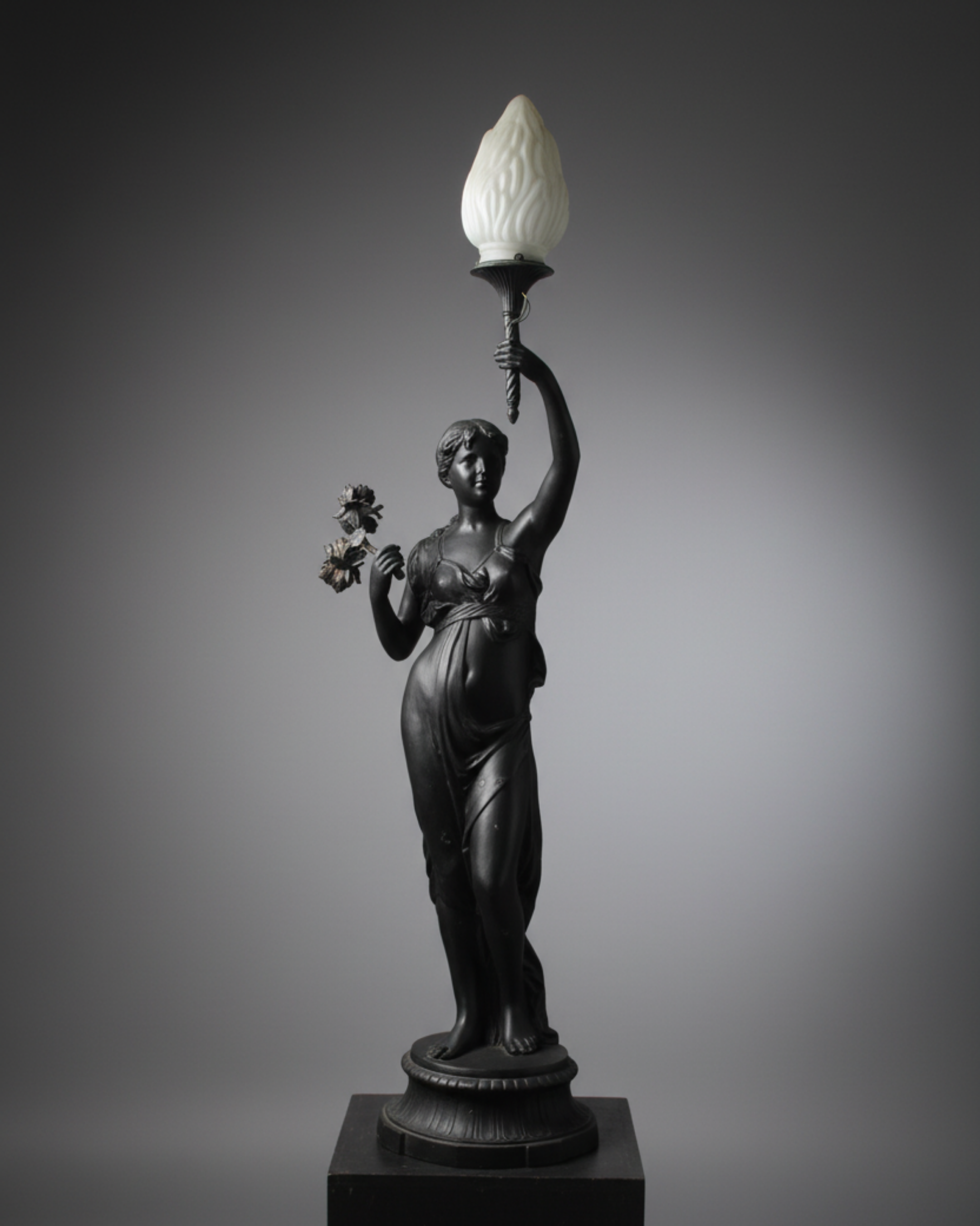 Statue of a woman holding a lamp against a gray background