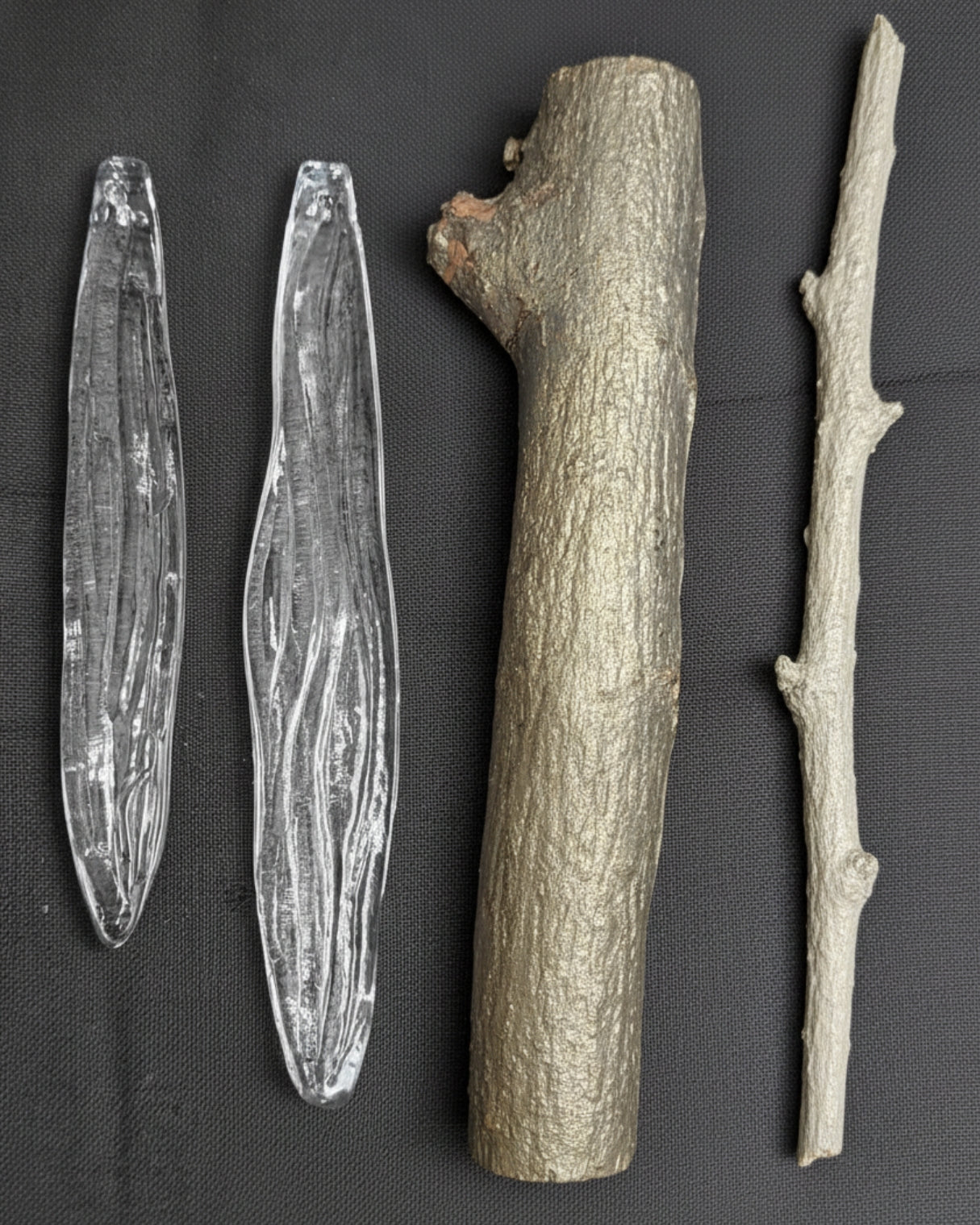 Vriksha Jyoti inspired by weeping willow Two clear stone tools and two wooden sticks on a dark surface