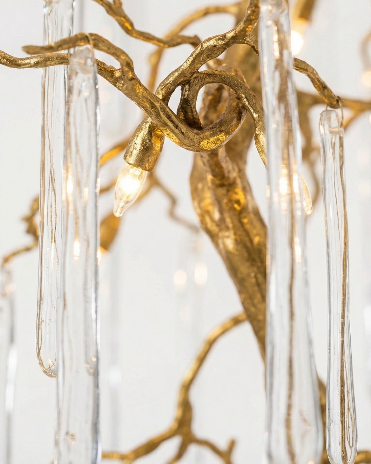 Vriksha Jyoti inspired by weeping willow Gold branch-like fixture with clear glass elements on a white background
