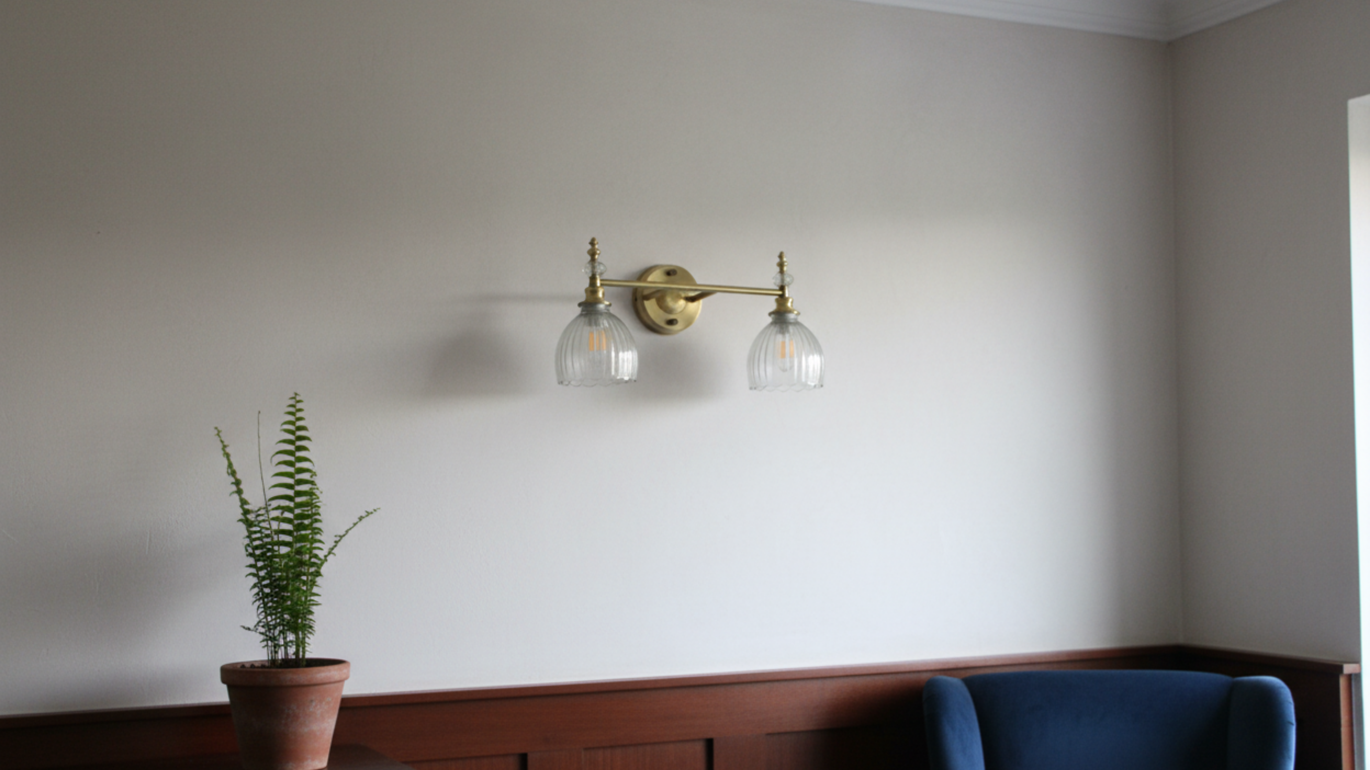 Crystal Crown Double Wall Light by Aartaa Decor illuminating modern living room – elegant brass and glass designer wall sconce