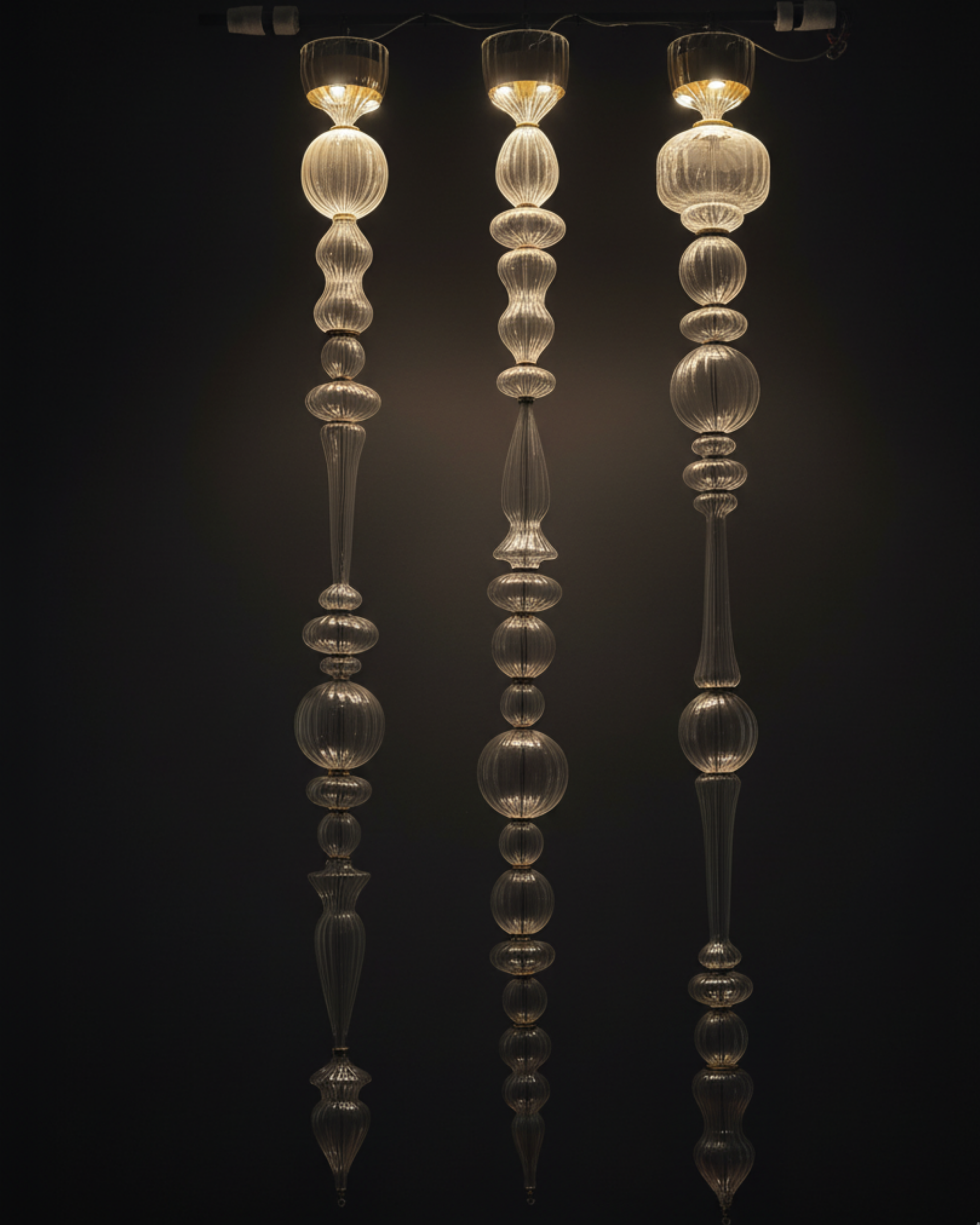 Three glass pendant lights with a dark background