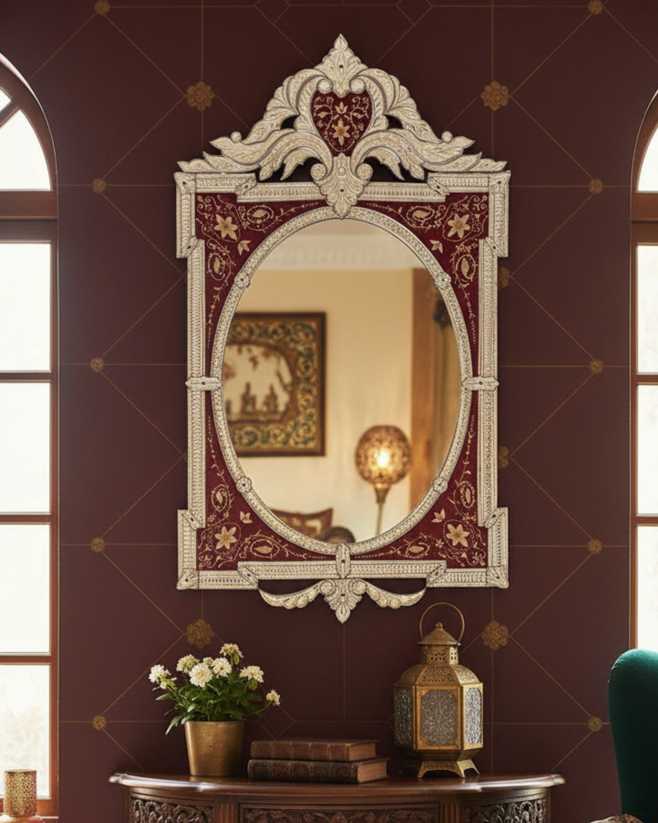 Decorative mirror with intricate design on a wall with floral arrangement and lantern.