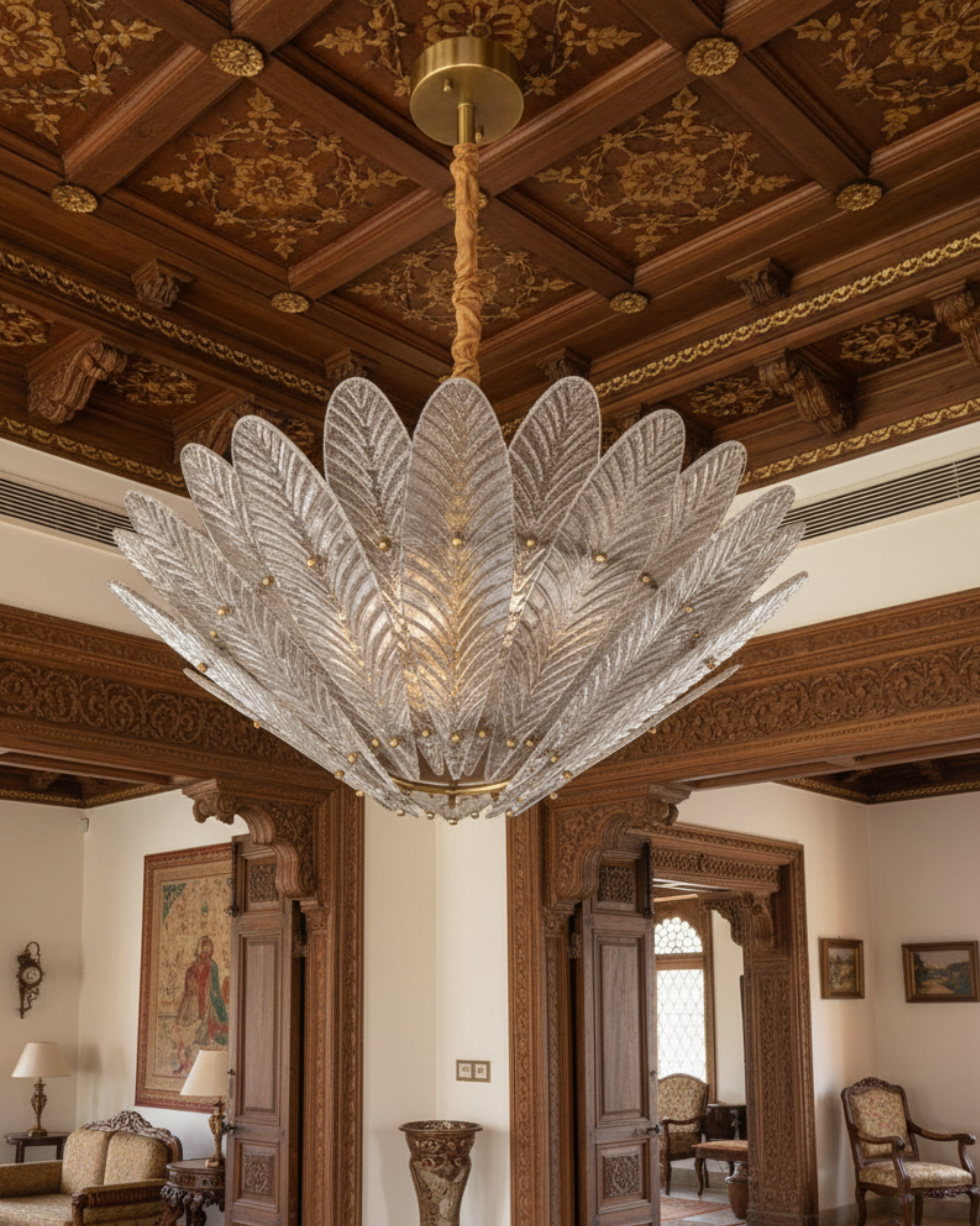 Decorative chandelier hanging in a room with wooden ceiling and furniture.
