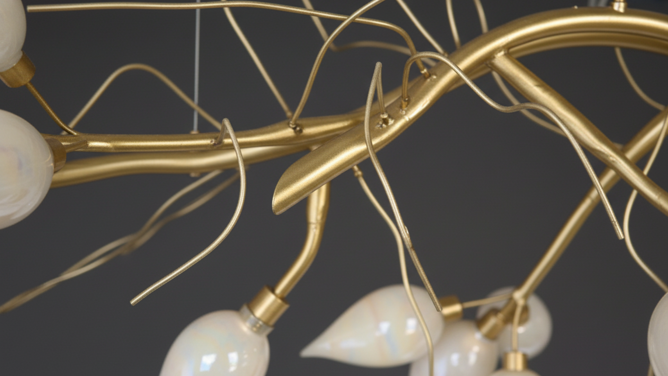 Gold chandelier with white glass shades on a dark background