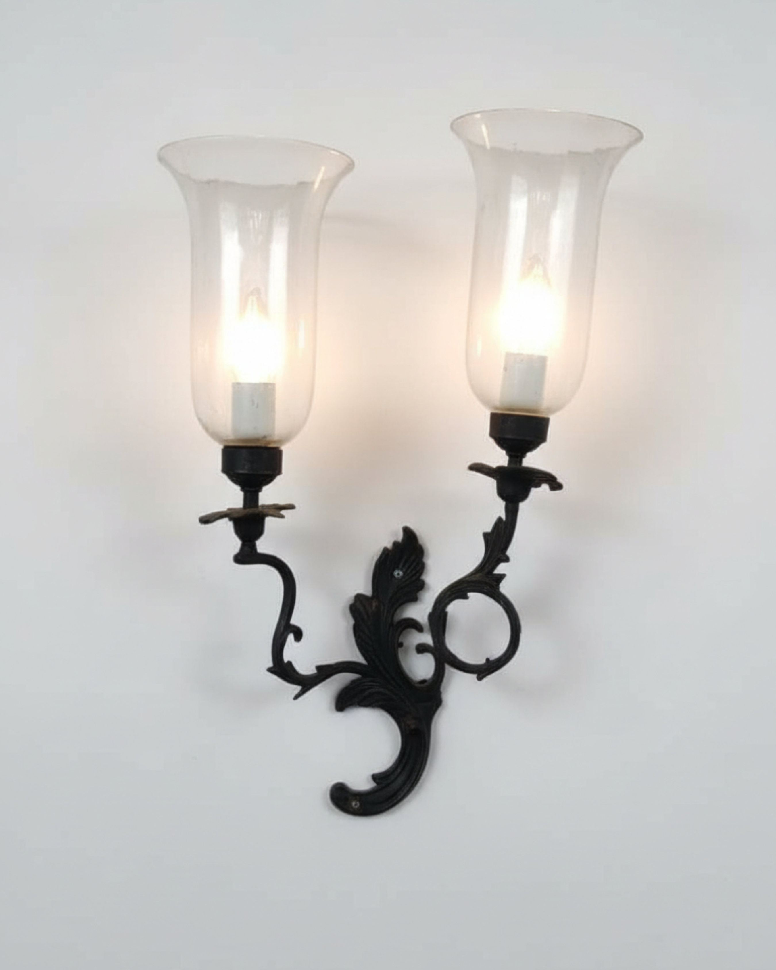 Decorative wall sconce with two candle-style lights on a white background