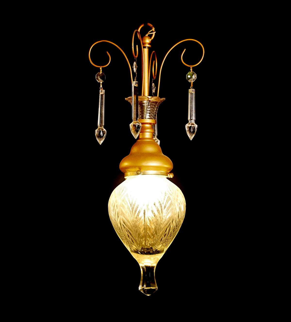 Elegant gold and glass teardrop pendant lights with crystal accents, hanging in a stylish room with yellow walls and a cozy yellow armchair.